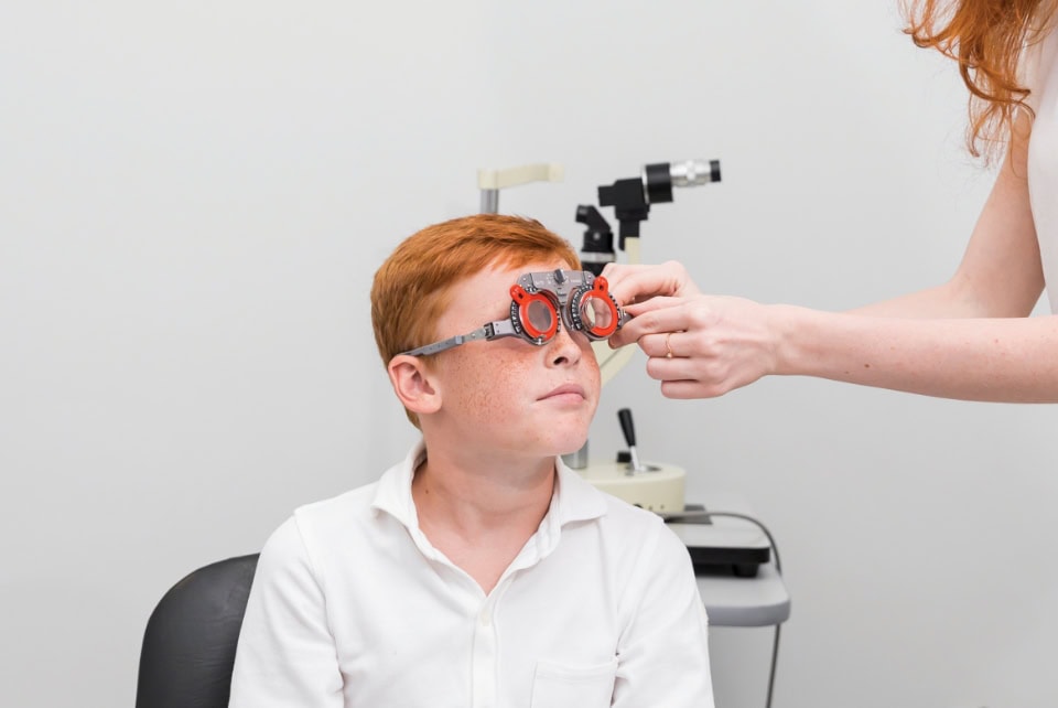 Female Ophthalmologist Examining Boy Eyes With Optometrist Trial Frame