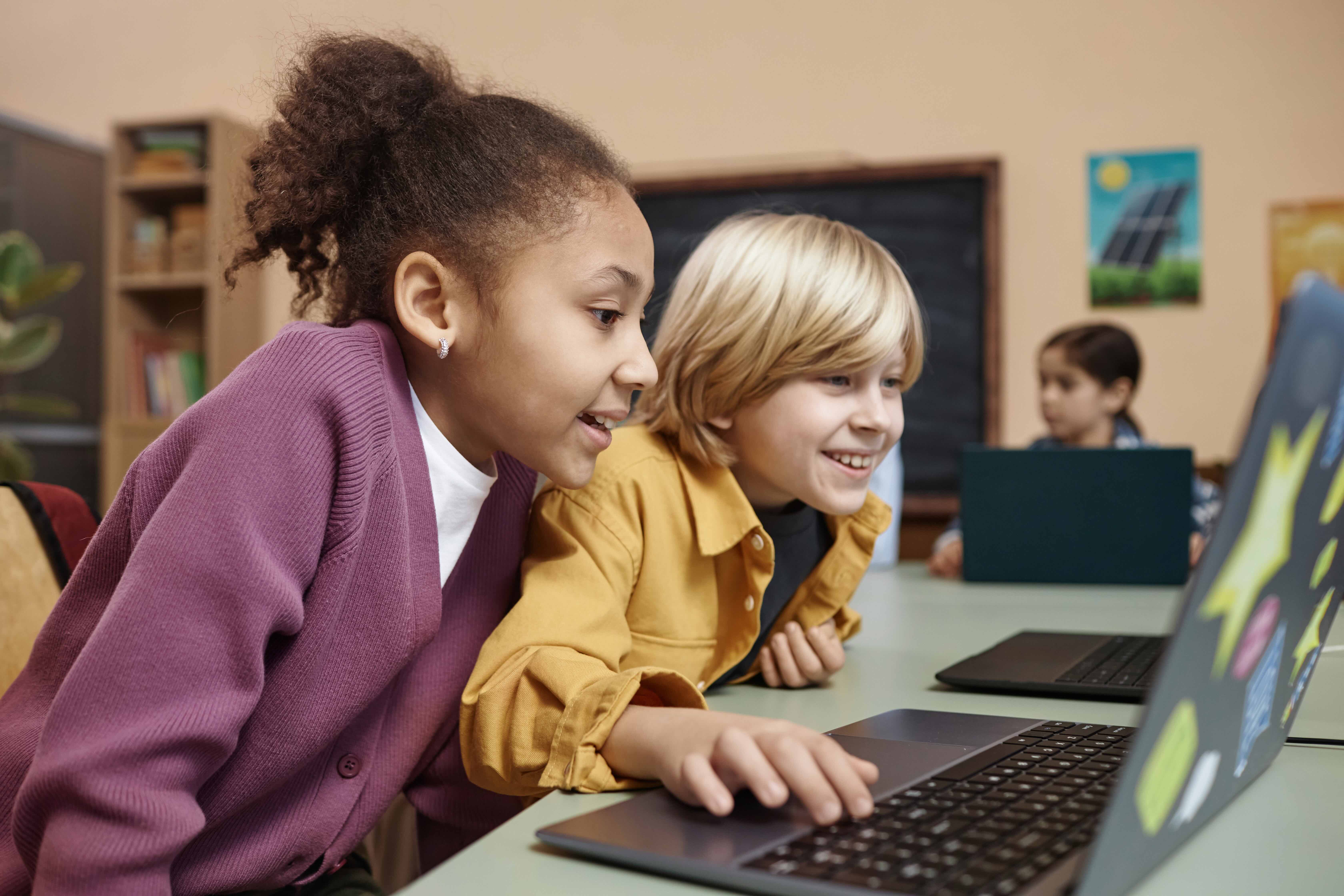 Two Excited Kids Looking At Computer Screen In School
