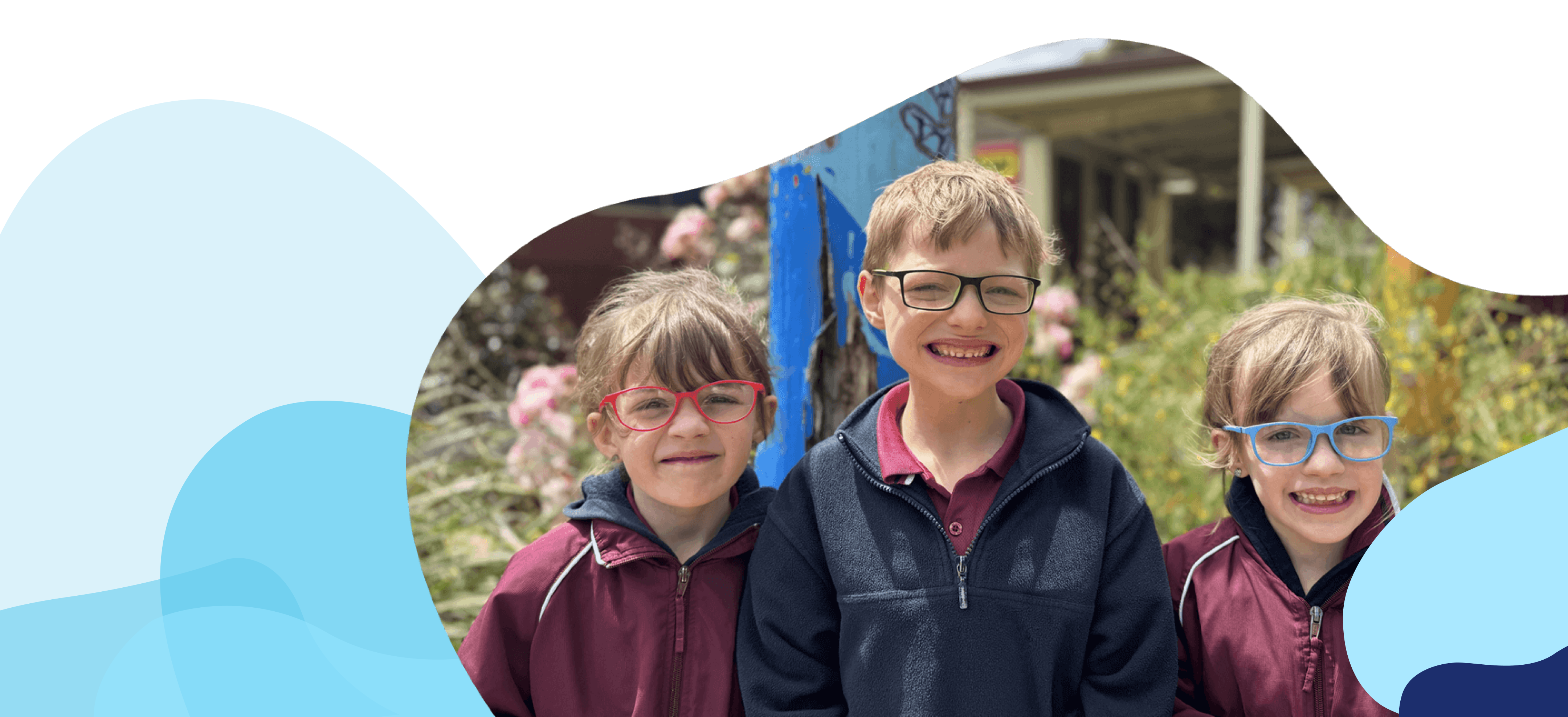 Three kids with glasses standing outside of school